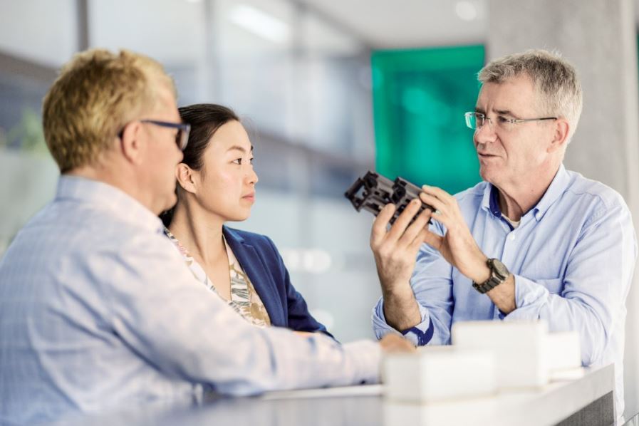 Three people talking and one is holding something in his hand.